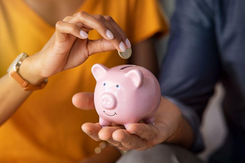 Darüber hinaus kannst du Olivenölseife vielseitig verwenden, womit du zusätzlich Geld sparen kannst. Eine Frau, die ein Sparschwein hält.